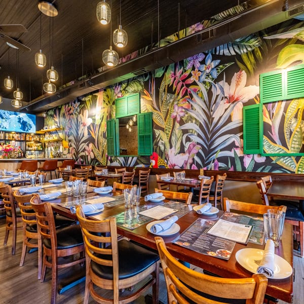 Siam Thai Restaurant dining room with tropical mural, wooden tables, chairs, and a bar.