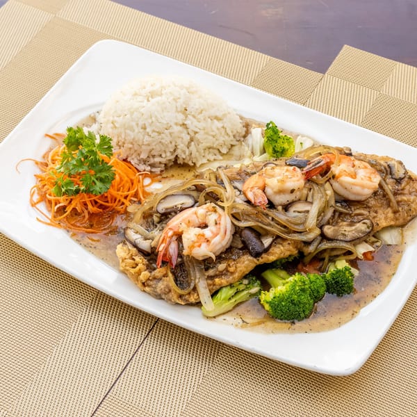 Siam Thai Restaurant's fried fish with shrimp, mushrooms, onions, broccoli, and rice on a white plate.