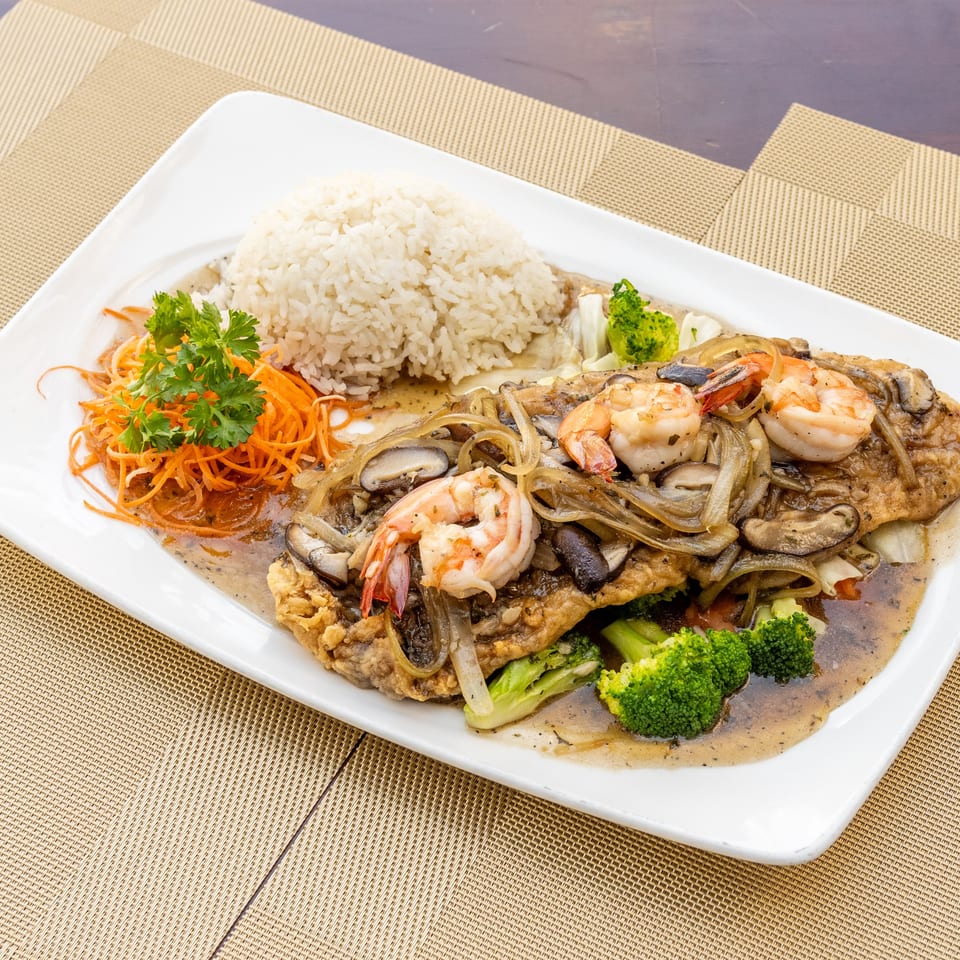 Siam Thai Restaurant's fried fish with shrimp, mushrooms, onions, broccoli, and rice on a white plate.